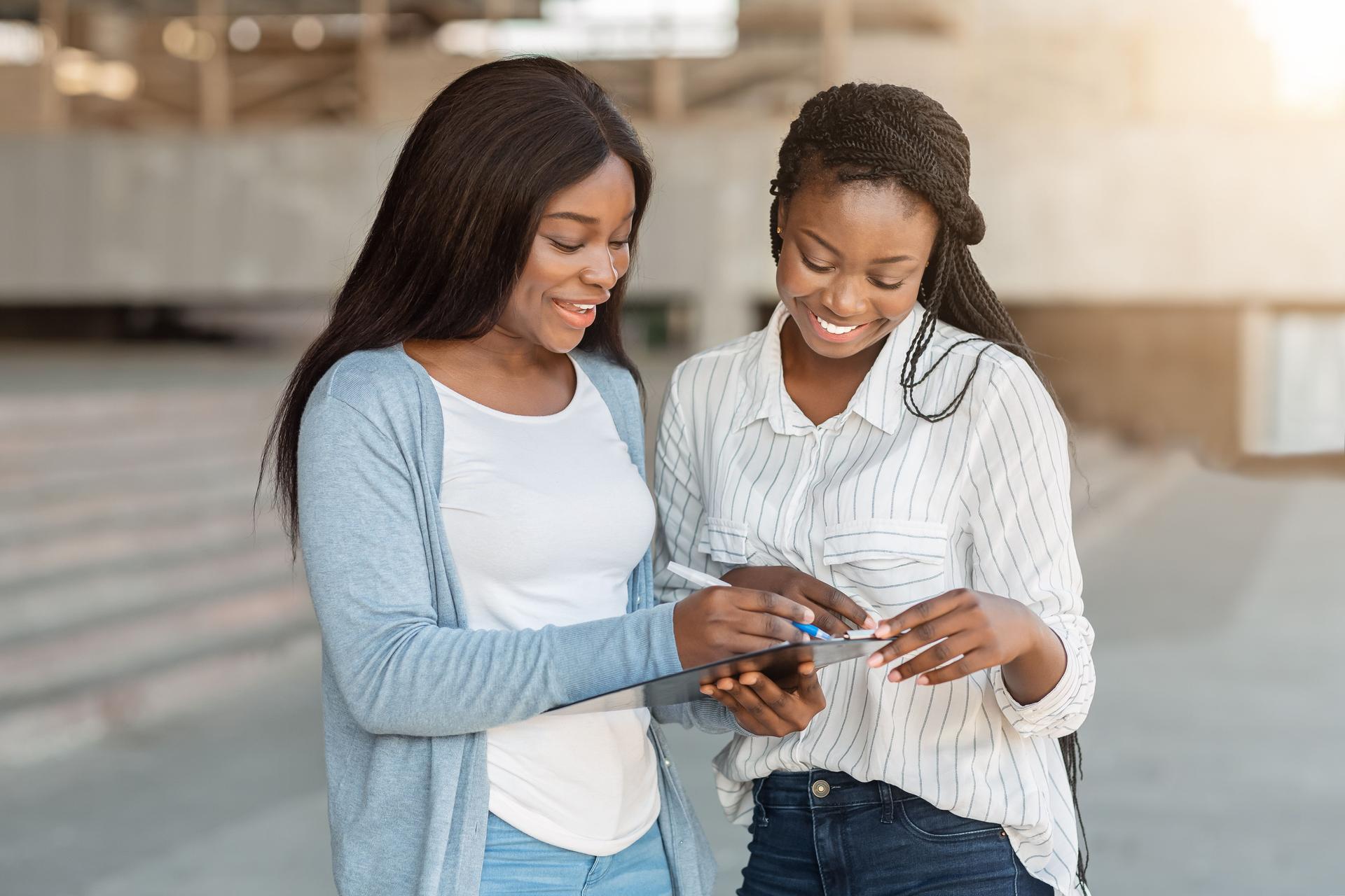 Afro female interviewing young woman on street for social research
